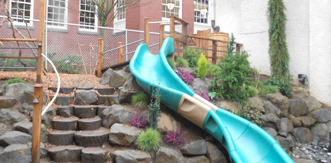 preschool natural playground boulders and slide